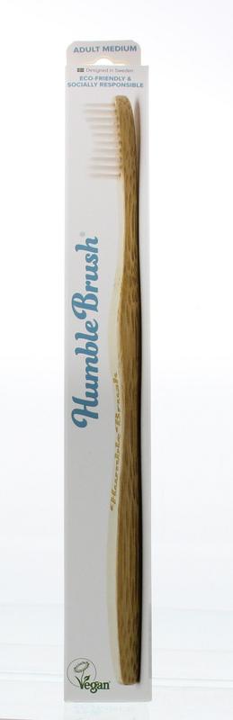 The Humble Co bamboo medium toothbrush with white handle and bristles, eco-friendly design, positioned on a clean surface.